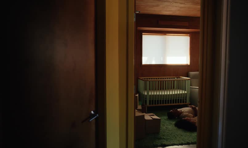 A woman is laying on the floor of a babys room and a man lays down next to her