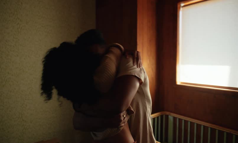 A man and woman look into a crib then hug