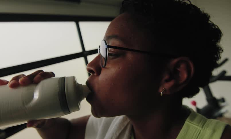 Woman drinking water from a white plastic bottle