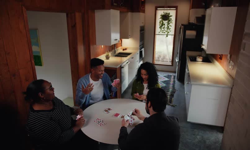 A group of friends are playing cards while sitting at a kitchen table