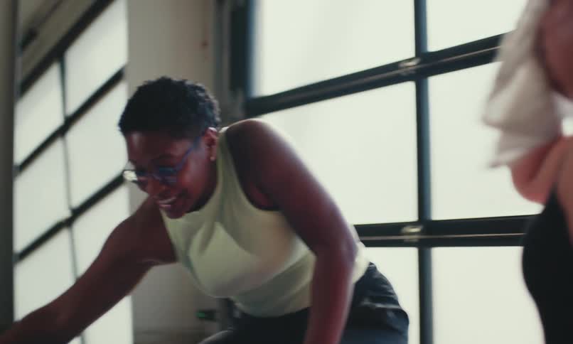 Women sit on the floor after exercising wipe sweat from their faces with small white towels and finish with a fist bump