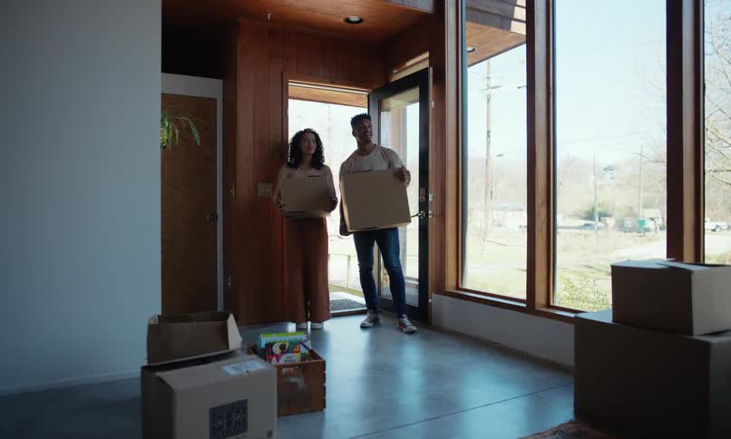 Excited young couple carrying boxes then hugging moving into thier new home