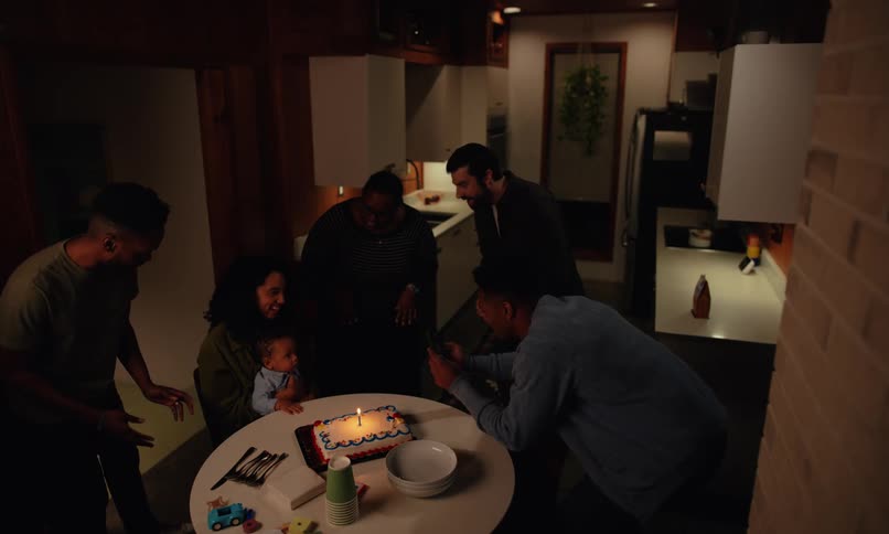 Family and friends celebrating babies first birthday at dining table in small kitchen