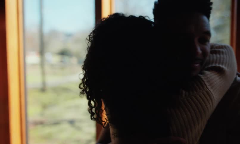 A man and a woman happily hugging each other and then they start looking out the window at the outside environment