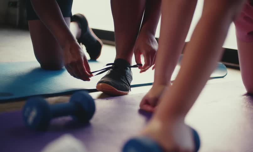 A woman ties her shoes in the gym