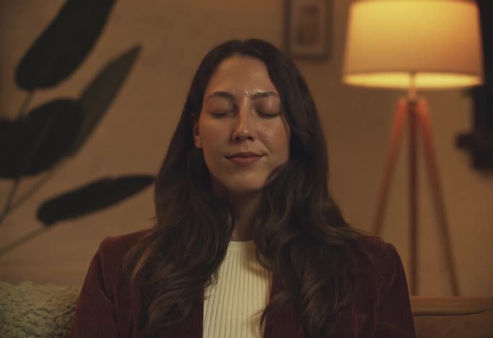 Woman sitting closing her eyes and taking a deep breath