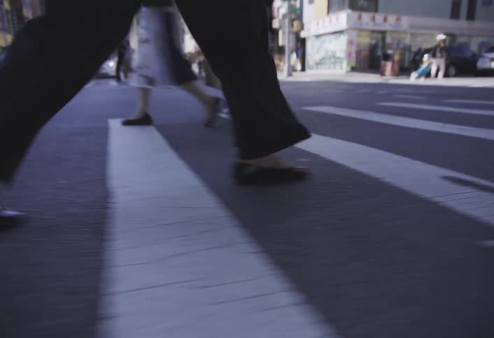 Pedestrians walk across a crosswalk in an urban area on a sunny day
