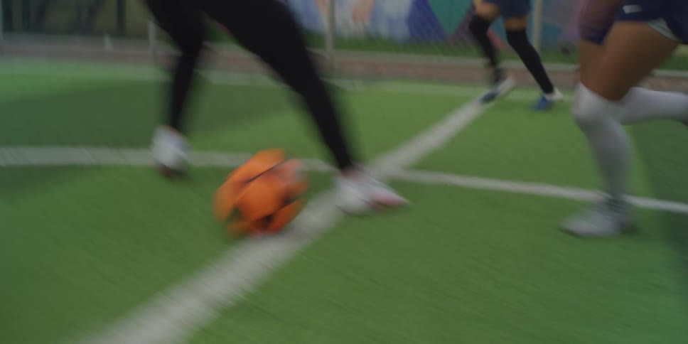 Women playing soccer on a pitch with one skillfully dribbling past an opponent before kicking the ball into the back of the net
