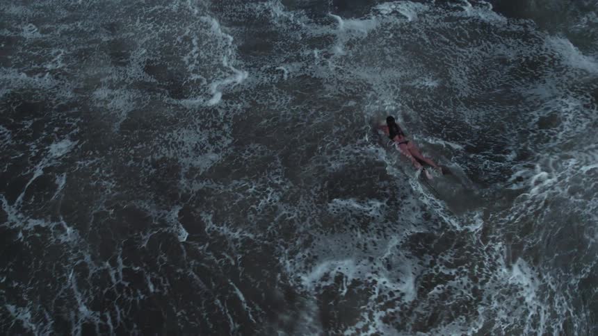 Woman swimming on surfboard in rough sea