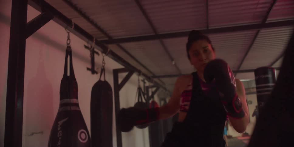 Woman wearing gloves punching and kicking a punching bag at a gym
