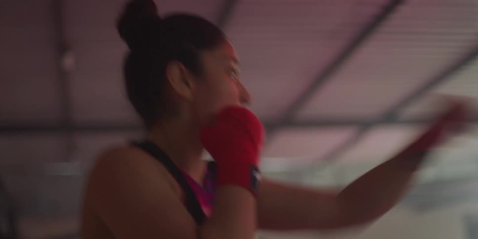 A woman wearing red gloves is practicing kickboxing demonstrating both punches and kicks