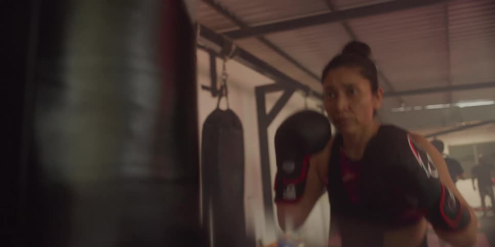 Woman with gloves punching a punching bag at a boxing gym