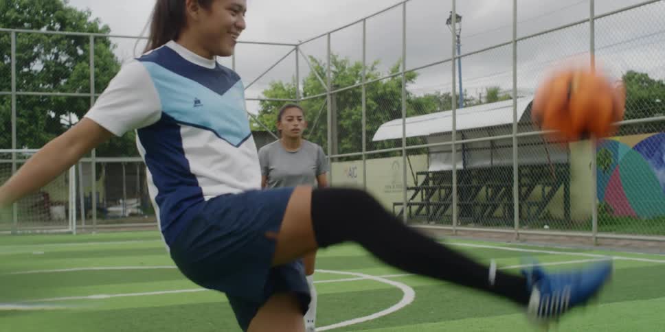 Three women playing soccer on an outdoor field