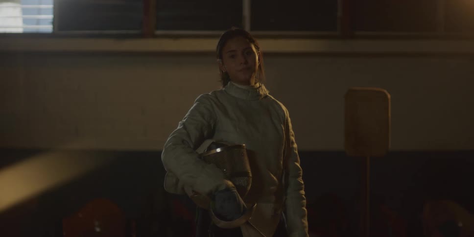Female fencer removes her fencing mask and stands with it under her arm