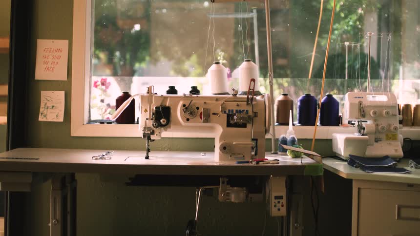 Sewing machine with spools of thread on a bench next to a window