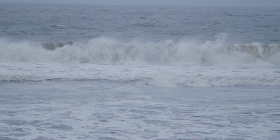 A woman lying on a surfboard paddling over a wave in the ocean