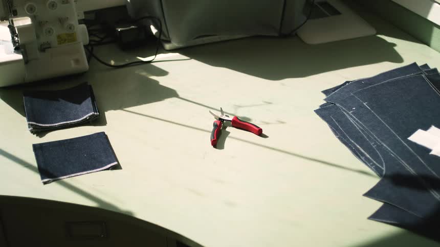 Pliers on top of a table with denim fabrics