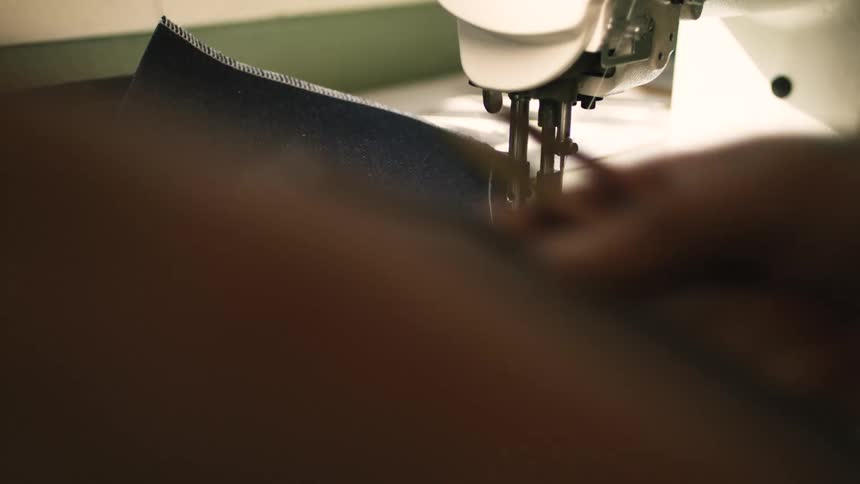 A man picking up fabrics and cutting loose threads with scissors