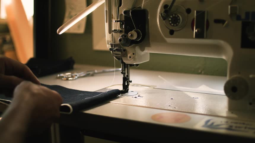 A man inserting the needle into the sewing machine