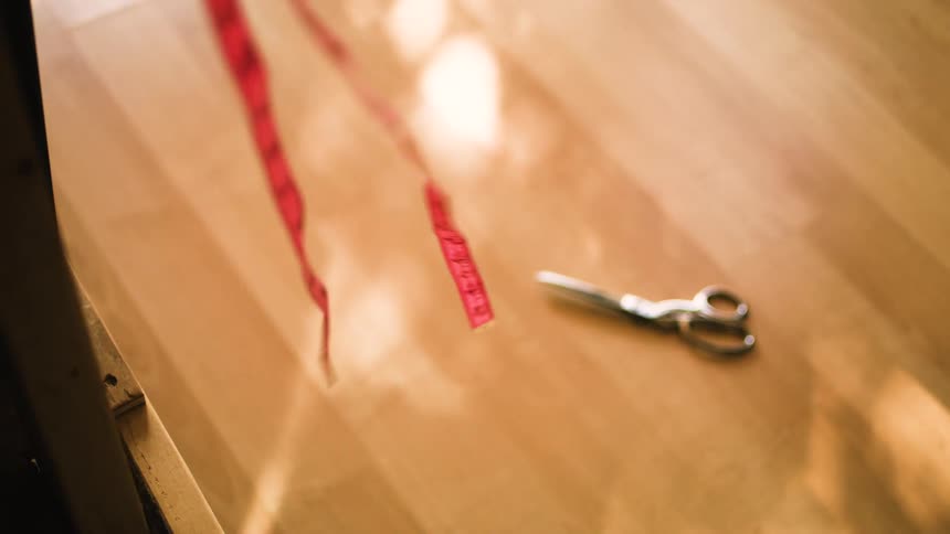 Red measuring tape in the foreground and scissors in the background