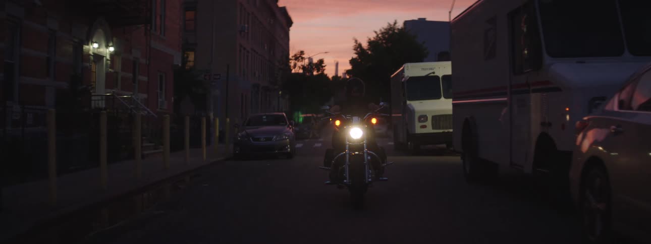 A motorcycle turns in the intersection at sunset