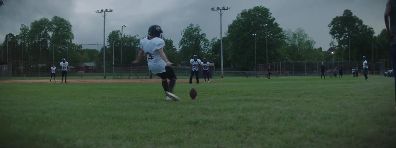 A football player kicks a ball across a field during football practice