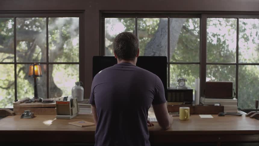 Man works at a computer and drinking coffee
