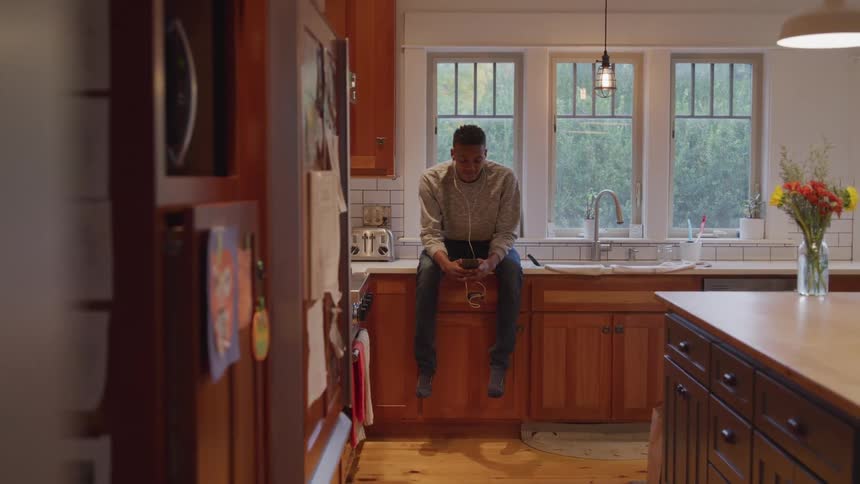 A man sits on the kitchen counter