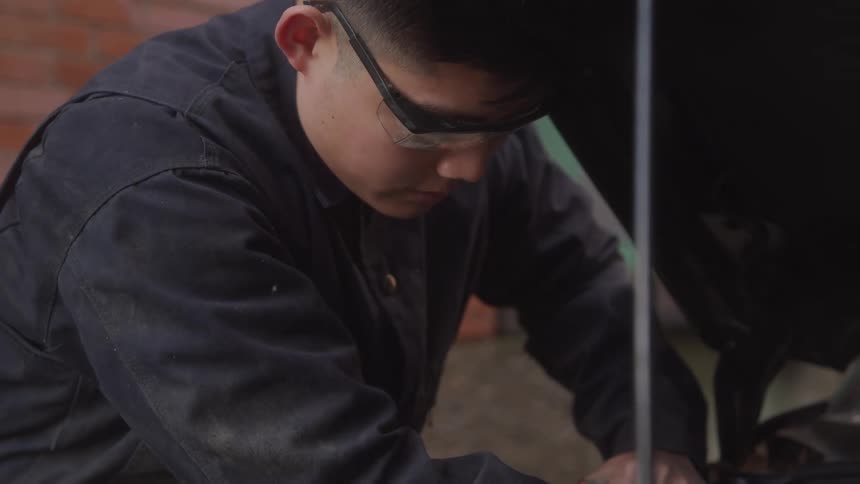 Mechanic wearing protective glasses working on a vehicle engine
