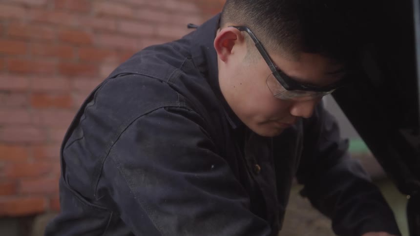 Man with protective glasses working on a vehicle engine