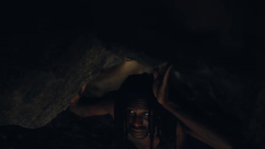 Man touches the low ceiling while moving through a cave