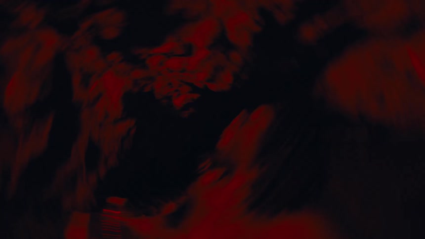 Silhouette of a shirtless person inside a cave with red lighting