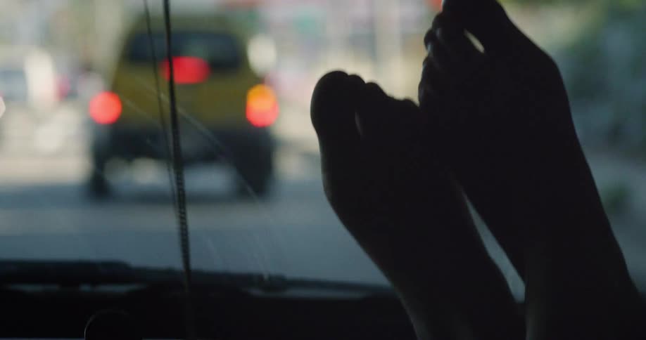 Closeup of a persons feet on the front panel of a moving vehicle