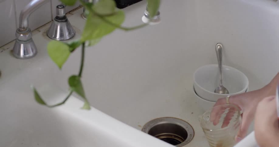 A woman pours her drink in the drain