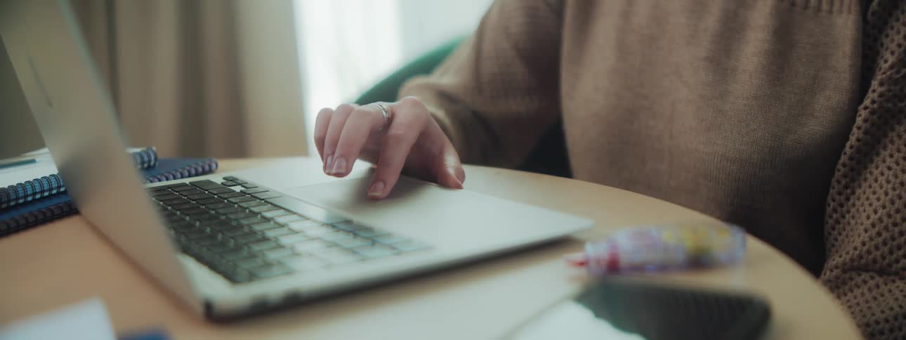 Pair of womans hands typing and using a laptop mouse pad