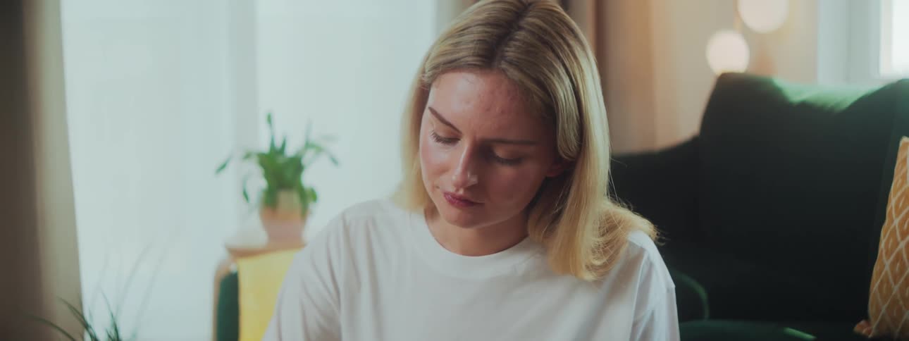 A woman in a room at a table drawing on her tablet