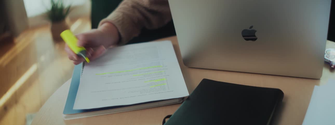 Woman sitting in front of a laptop in her living room highlights a document