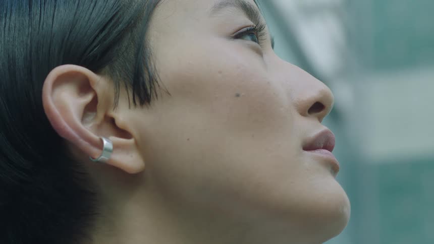 Woman wearing a cuff earring above her earlobe blinks slowly