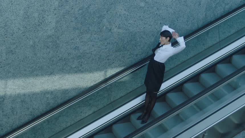 A flight attendant going down an escalator and stretching
