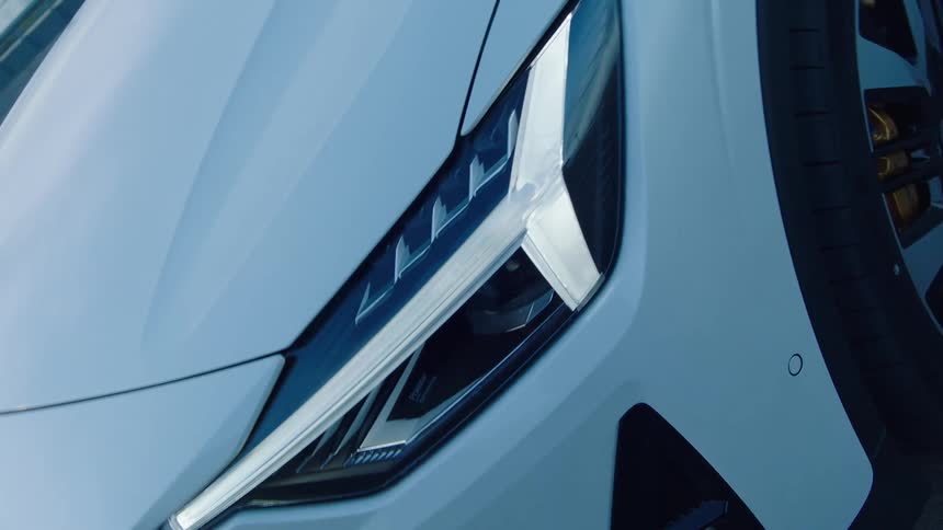 A white sedan car with stylish headlights parked under daylight