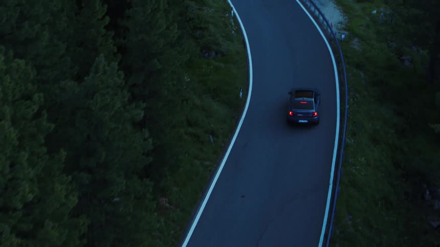 A car traveling on a road with trees and rocks nearby