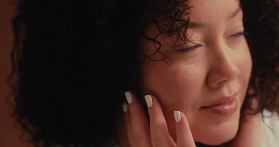 Close up face of a lady posing for picture smiling and touching her face