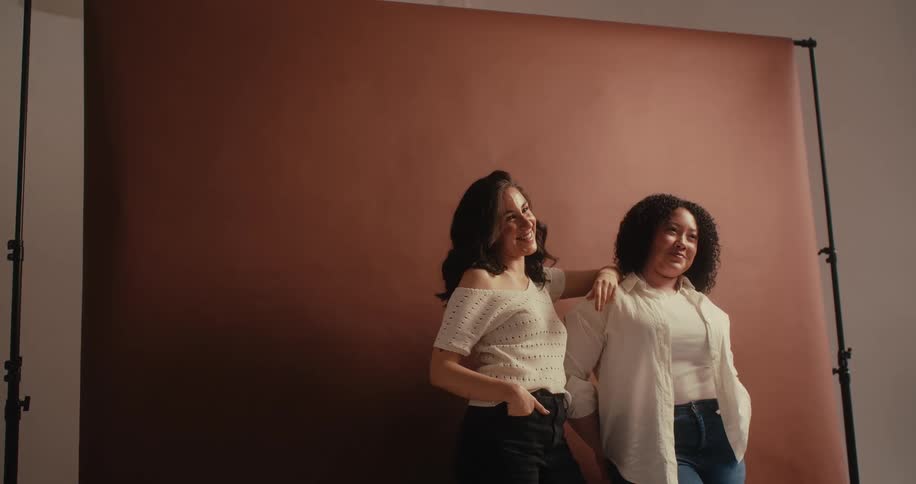 Two ladies at the studio in front of a backdrop casually laughing