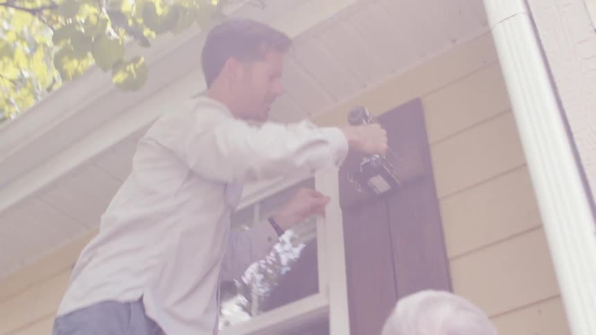 A man is drilling into the side of the home
