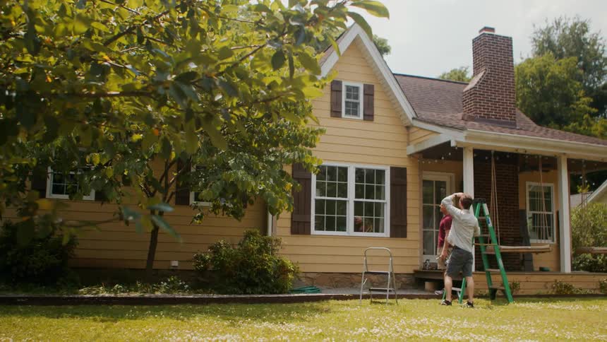 A father and son talk in front of the house