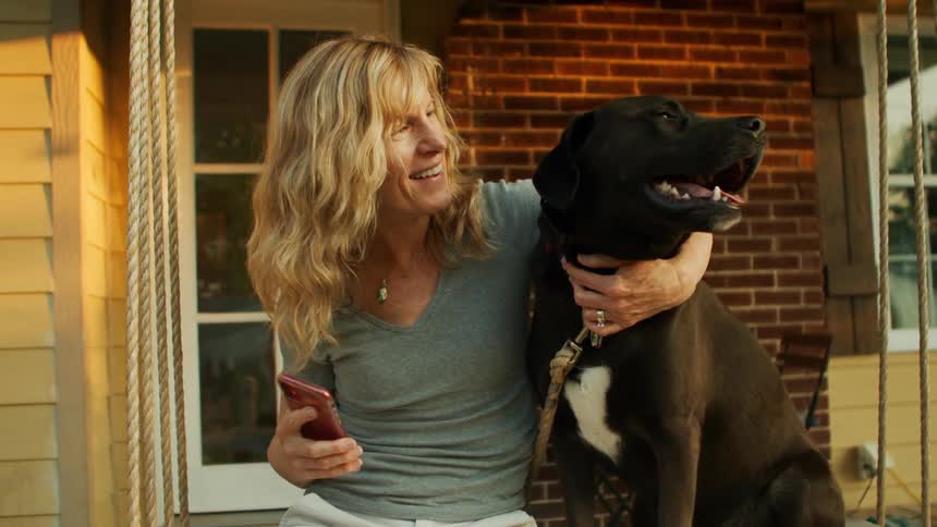 Woman sitting on a bench in her backyard next to her dog