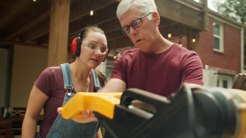 An older man teaching a young woman how to use the machine