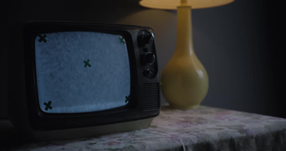 Static scrolling on an old tv with five xs on it sitting next to a lamp on a table