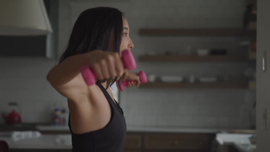 Woman doing weight lifting while in the kitchen