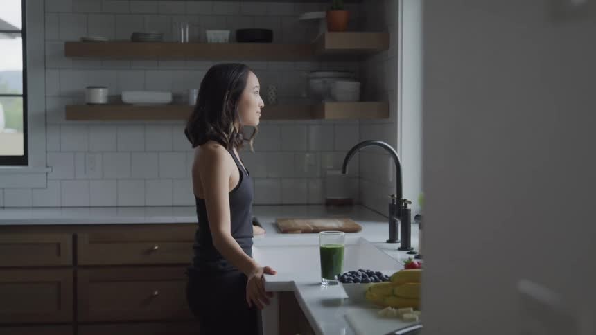 Woman standing in front of kitchen sink watching